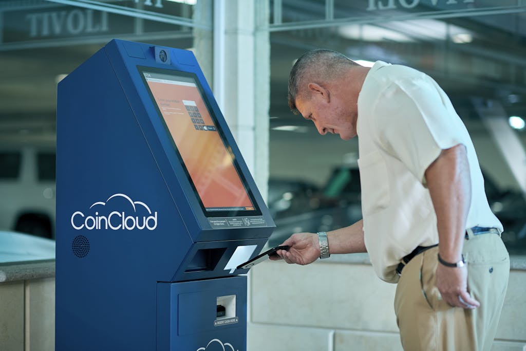 Adult man interacting with Coin Cloud digital currency machine indoors, demonstrating modern technology usage.